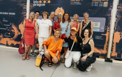Women Bitcoiners posing at the BTC Prague conference banner